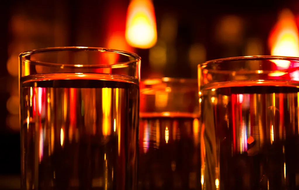 Glass som fanger det røde stearinlyset — siste glass for kvelden.